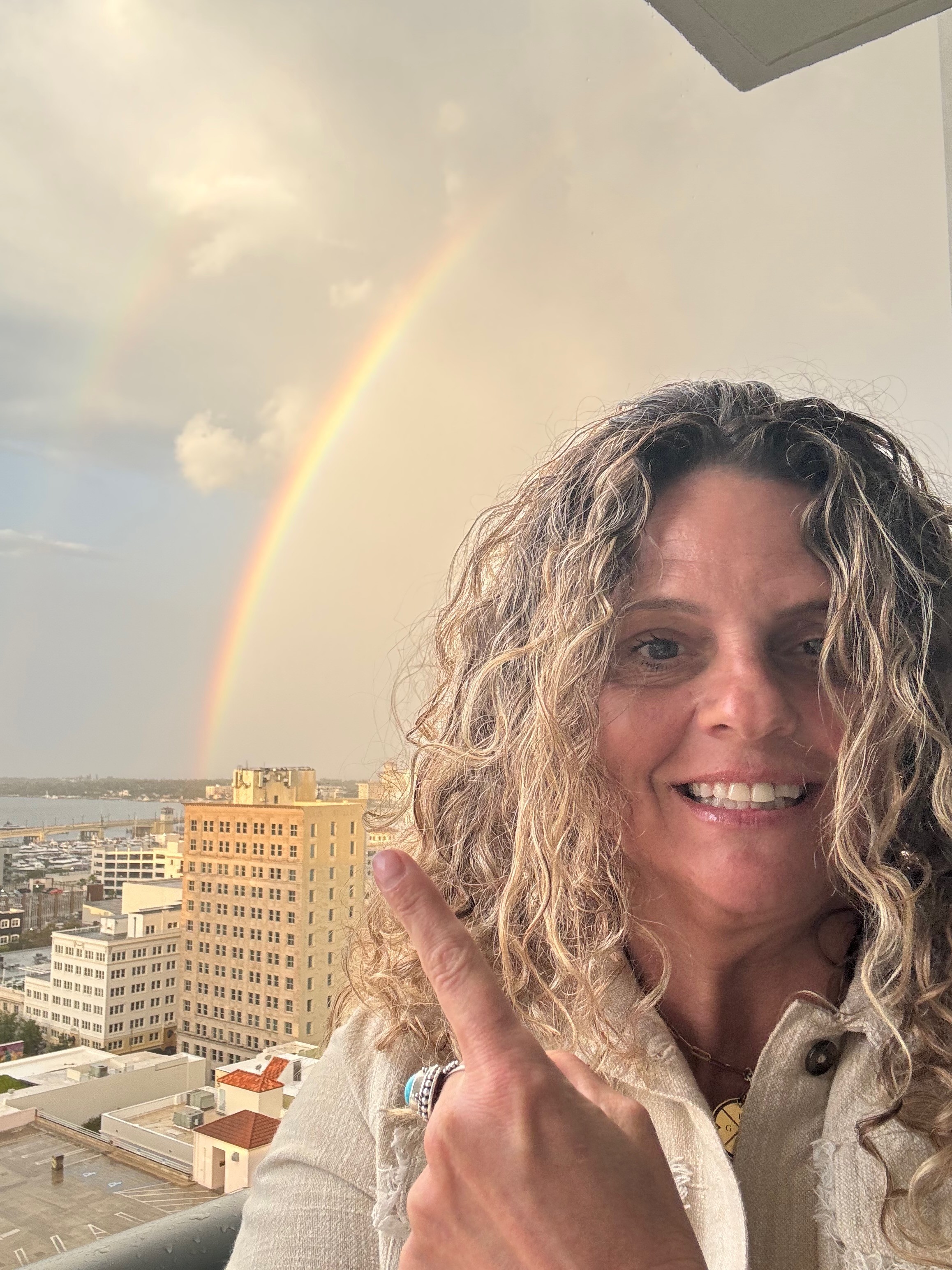 Kimberly Sheahan pointing to a rainbow over the city skyline and water